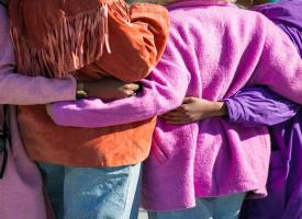 Women with arms wraps behind each others backs. 